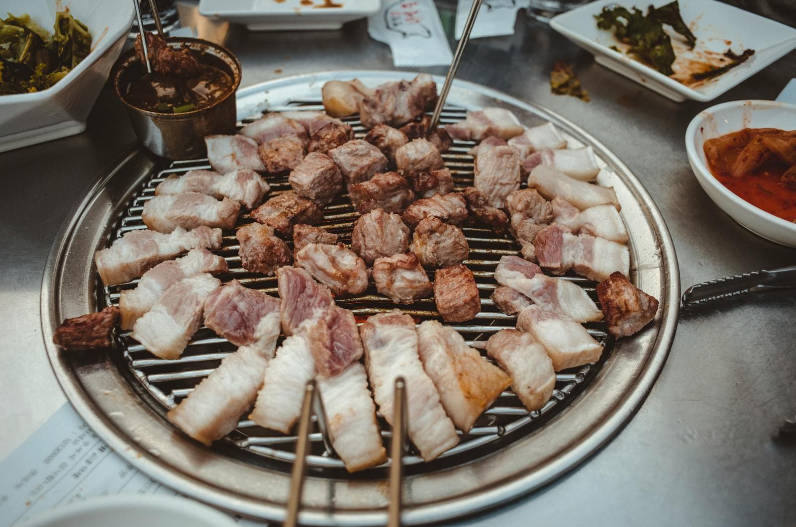 Bite-size pieces of samgyeopsal grilled on a circular Korean BBQ grate